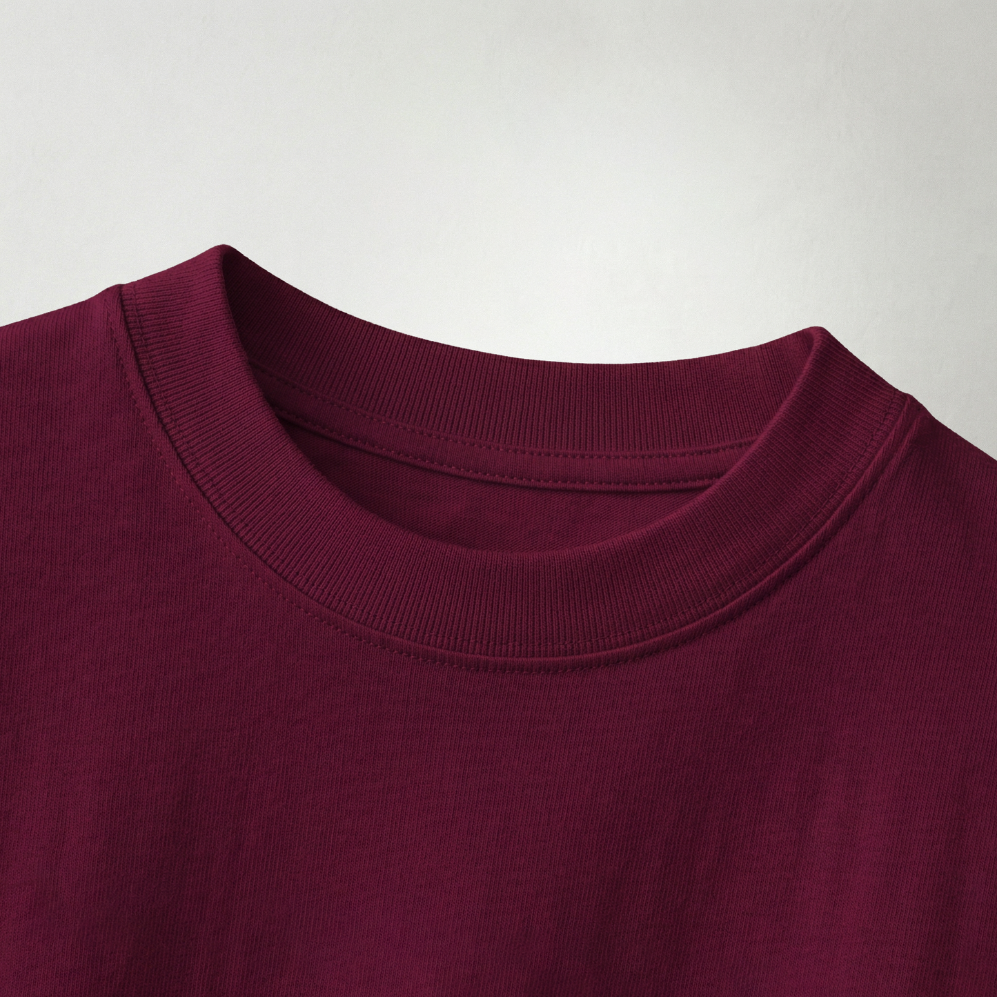 Close-up of maroon oversized t-shirt fabric and neckline showing soft cotton texture and stitching