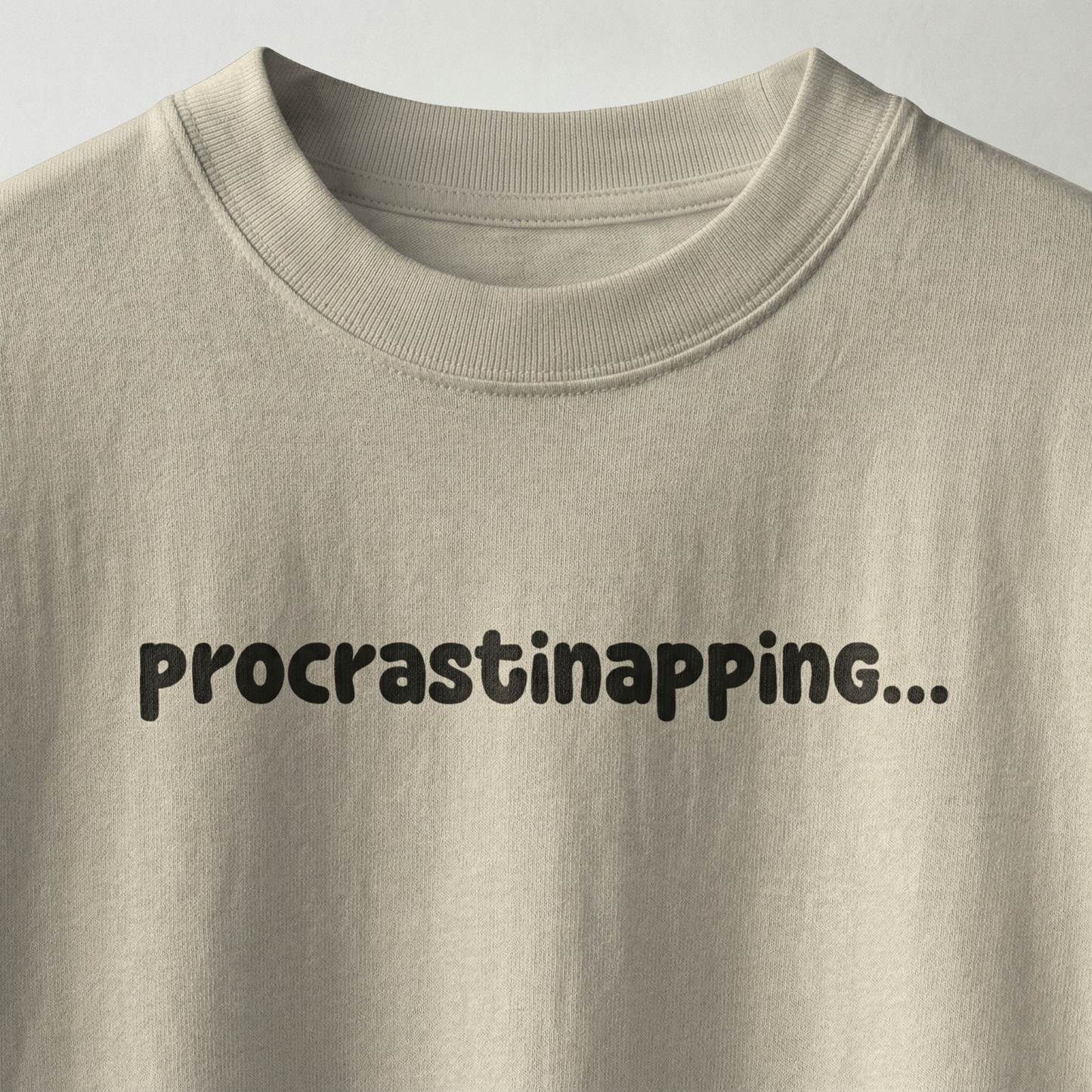 Beige oversized t-shirt with “procrastinapping” text printed in minimal playful font
