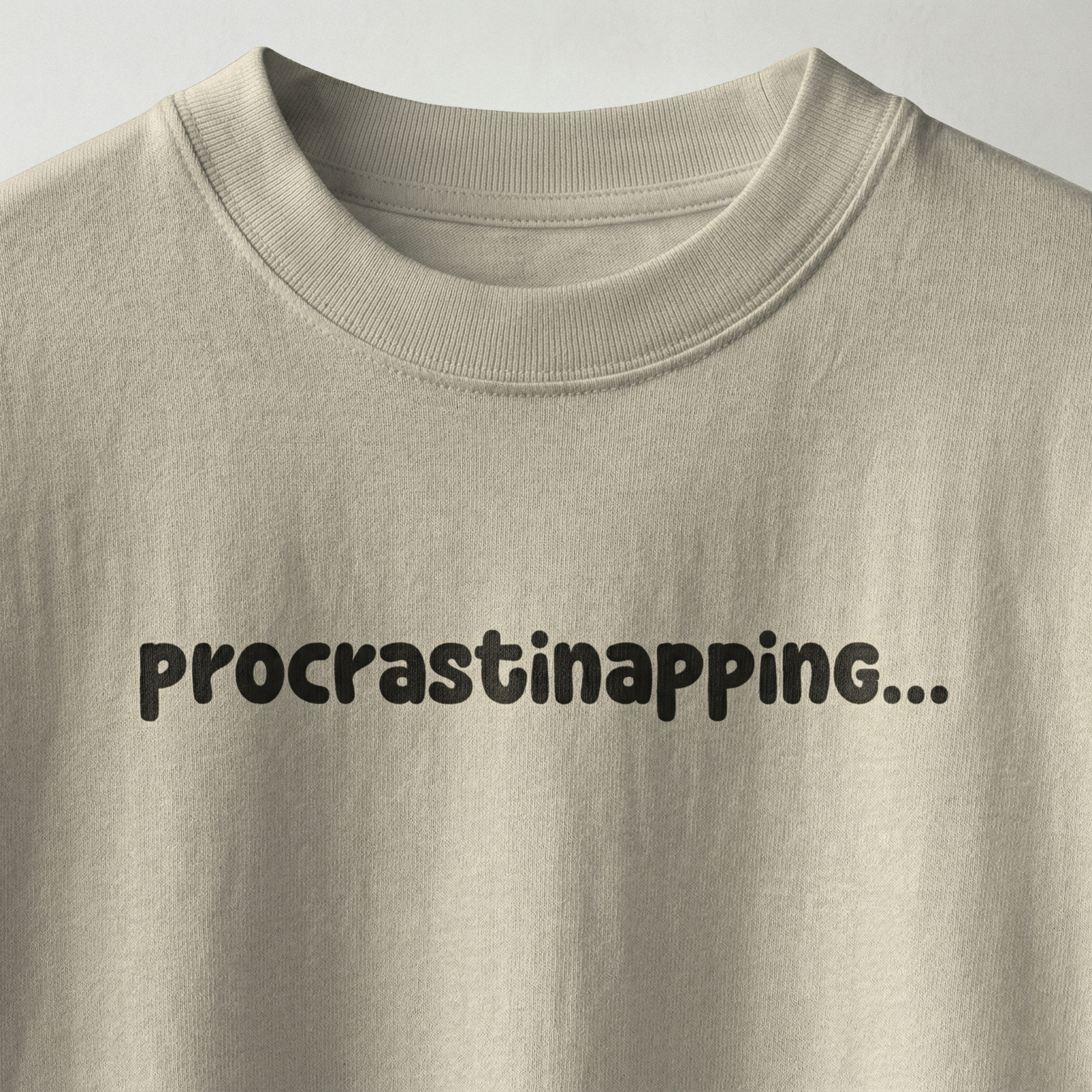 Beige oversized t-shirt with “procrastinapping” text printed in minimal playful font