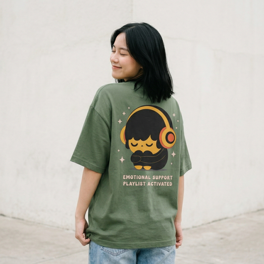 Woman wearing green oversized Emotional Support Playlist Activated graphic t-shirt outdoors