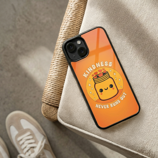 Kindness Never Runs Out orange glass iPhone case by Spiritual Kalakaar with cute jar illustration placed on woven chair in sunlight