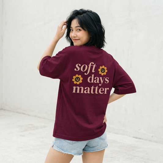 Woman wearing maroon oversized t-shirt back view with soft days matter text relaxed aesthetic