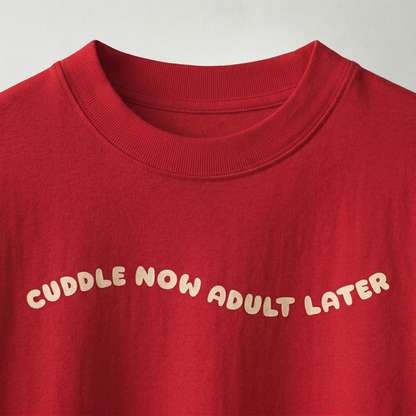 Close-up of “cuddle now adult later” text on red oversized t-shirt