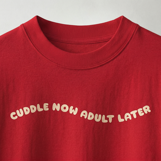 Close-up of “cuddle now adult later” text on red oversized t-shirt